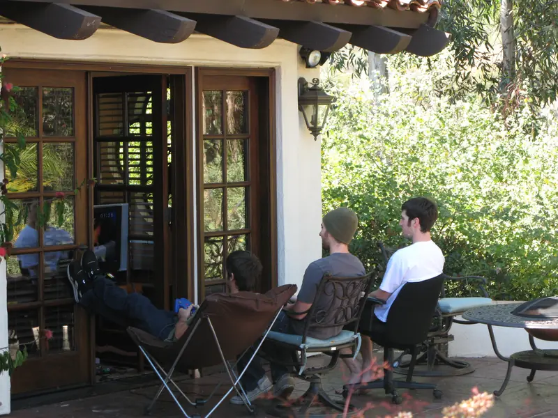 Three guys playing video games outside the poolhouse
